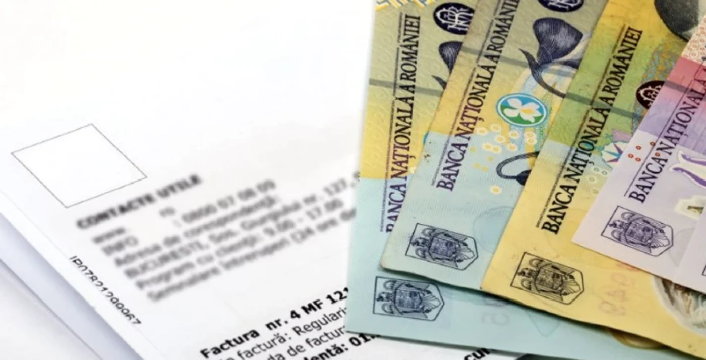 Bancnote de 100 și 50 de lei puse peste o factură la energia electrică